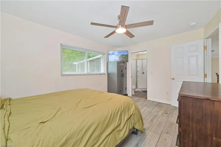 Bedroom featuring wood-finish flooring, a contemporary ceiling fan, and a window with white blinds