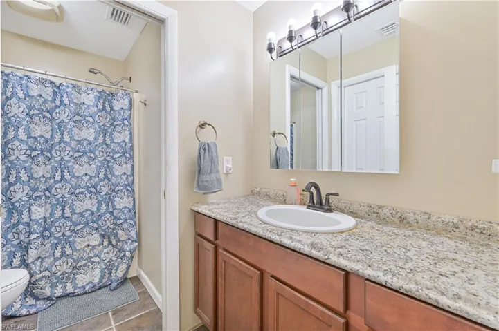 Bathroom featuring a vanity with an integrated sink, a gray speckled countertop, and wood-finish cabinetry