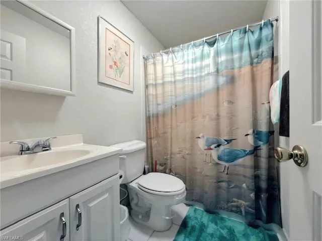 Full bath featuring a shower with curtain, vanity, tile patterned flooring, and a textured wall