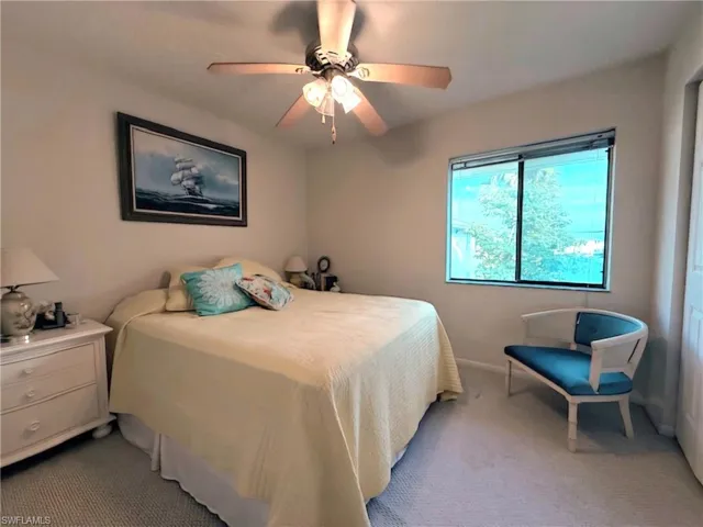 Carpeted bedroom with a ceiling fan and baseboards