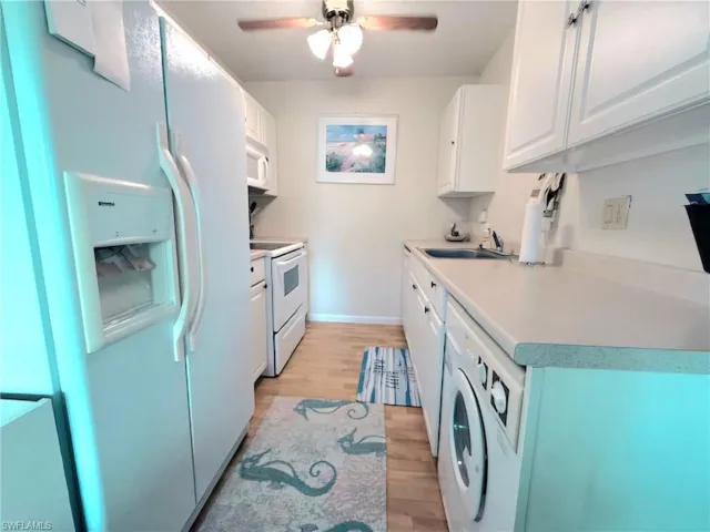 Kitchen featuring white appliances, white cabinetry, light wood finished floors, and light countertops