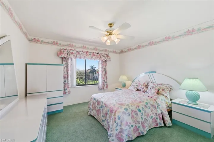 Carpeted bedroom with ceiling fan and baseboards