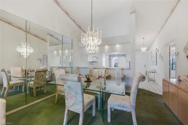 Dining space with hanging lights, dark colored carpet, and vaulted ceiling