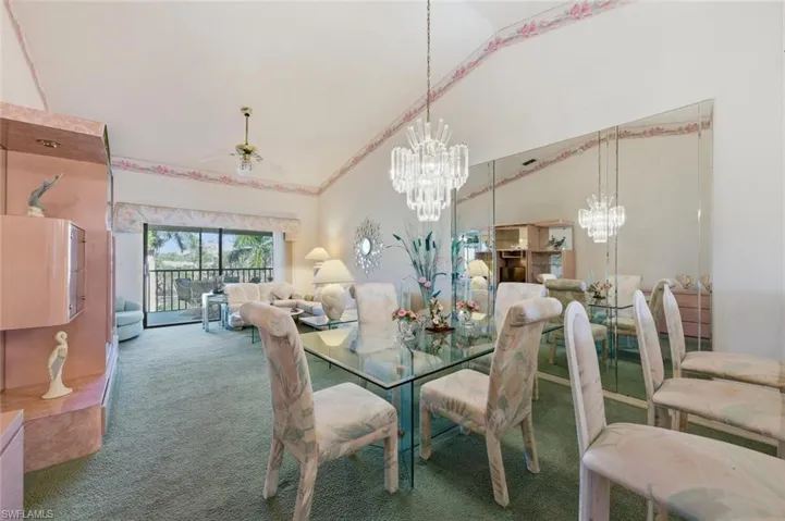 Dining space featuring carpet flooring, vaulted ceiling, hanging lights, and ceiling fan