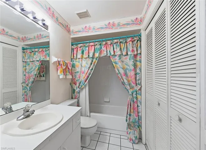 Full bath with a closet, vanity, and shower / bath combination with curtain
