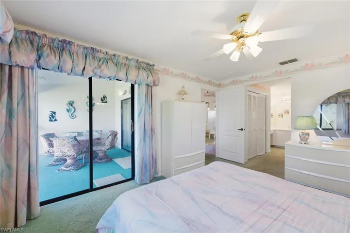 Carpeted bedroom featuring access to outside, a ceiling fan, and connected bathroom
