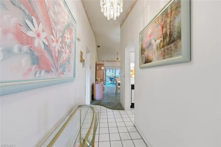 Hall featuring hanging lights, light tile patterned floors, light colored carpet, and ornamental molding