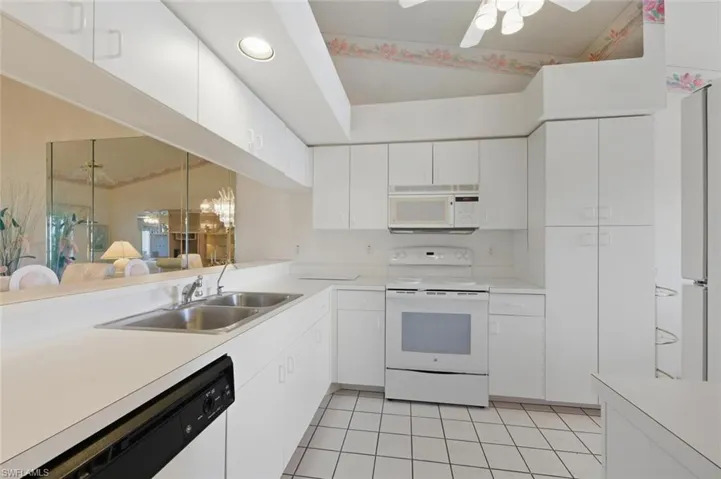 Kitchen with white appliances, light countertops, ceiling fan, white cabinetry, and light tile patterned flooring