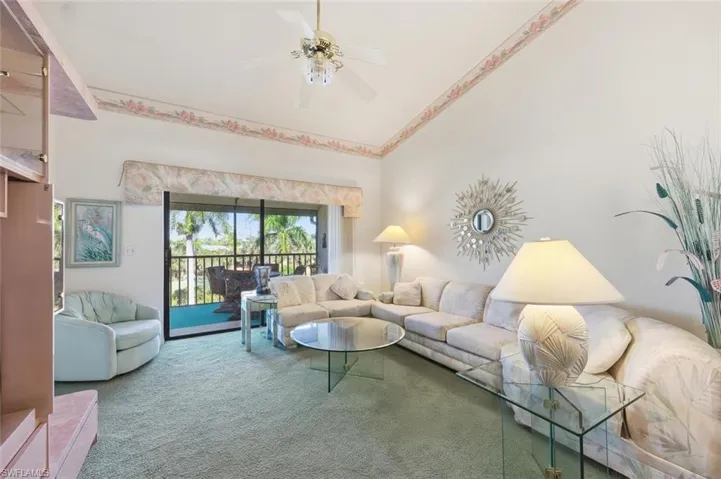 Carpeted living room with ceiling fan and lofted ceiling