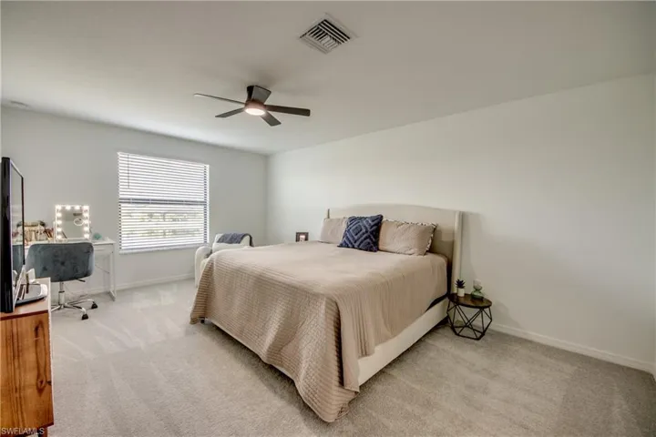 Bedroom with light carpet and a ceiling fan