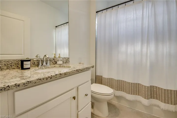 Bathroom with vanity, shower / bath combo, and tile patterned flooring