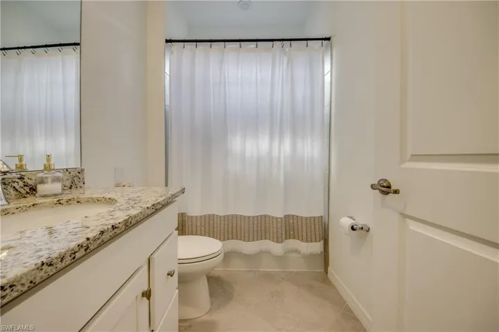 Full bathroom featuring vanity, shower / bath combination with curtain, and light tile patterned flooring