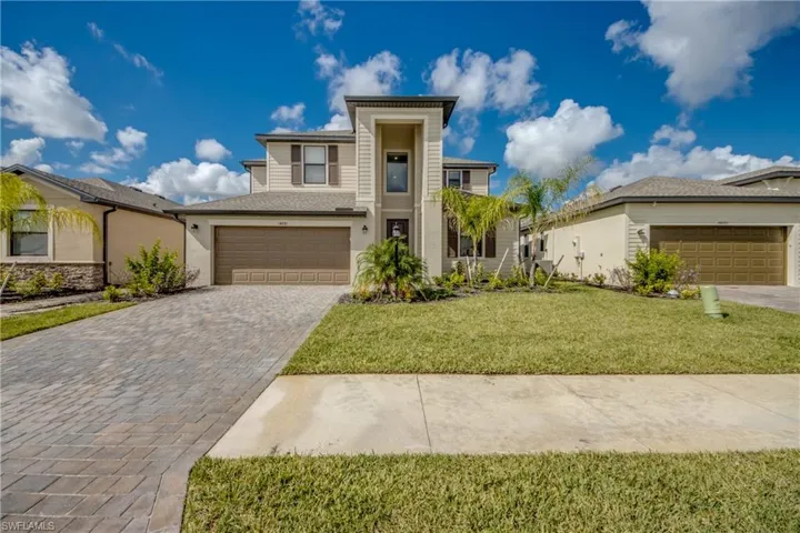 View of front of house with decorative driveway, a garage, and a front lawn