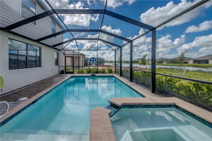 View of swimming pool featuring a sunroom, a patio, a pool with connected hot tub, glass enclosure, and a residential view