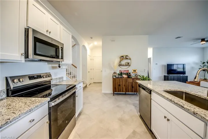 Kitchen with stainless steel appliances, white cabinets, and light stone countertops