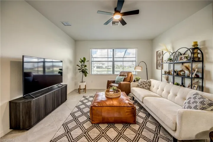 Living area featuring light tile patterned floors and a ceiling fan