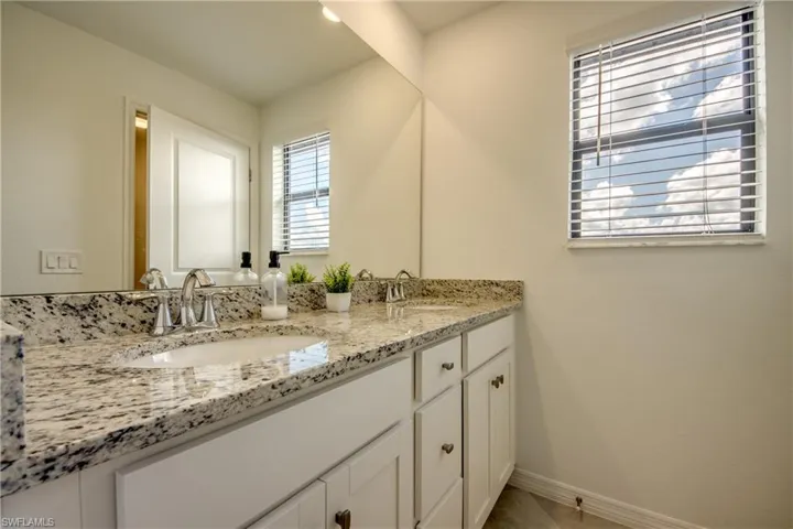 Bathroom with double vanity and baseboards