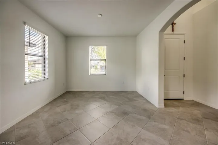 Empty room featuring arched walkways and light tile patterned floors