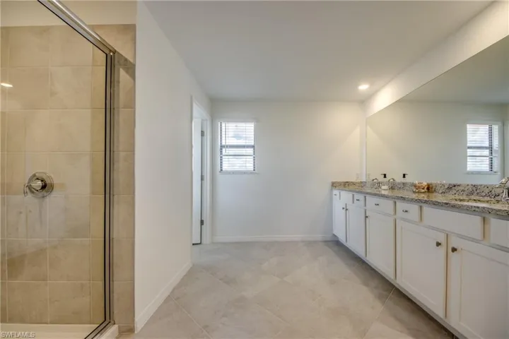 Full bathroom featuring a shower stall, double vanity, recessed lighting, and light tile patterned floors