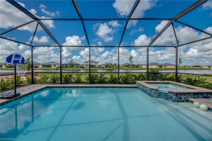 View of pool featuring a sunroom, a water view, a residential view, a pool with connected hot tub, and a lanai