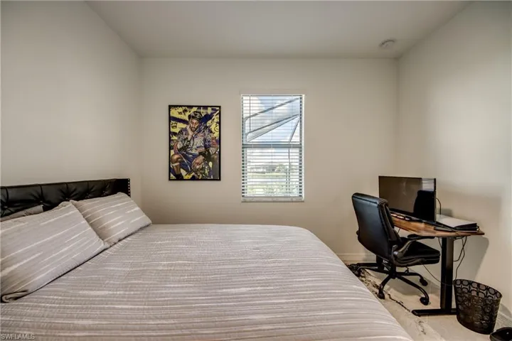 Carpeted bedroom with baseboards and an office area