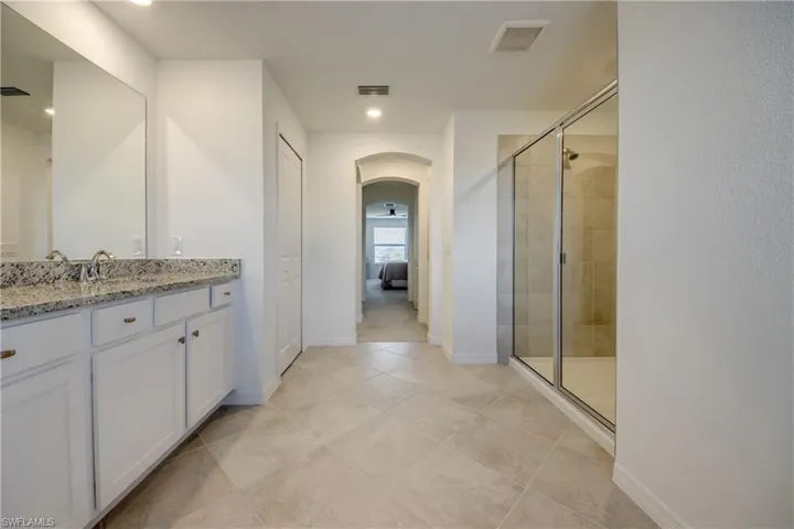 Full bath featuring vanity, a stall shower, ensuite bath, light tile patterned flooring, and recessed lighting