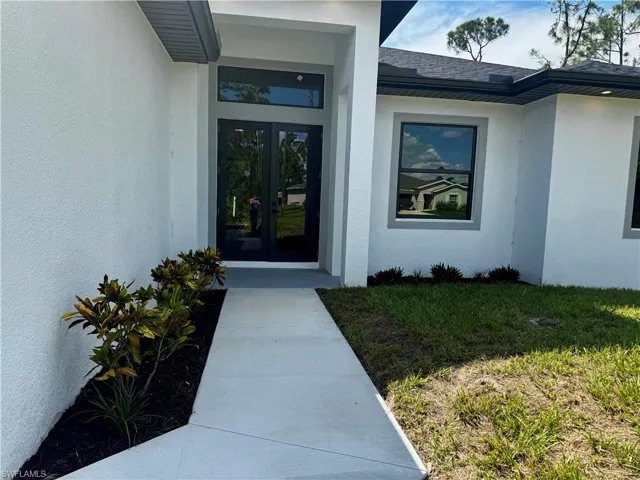 Property entrance with stucco siding, french doors, and roof with shingles