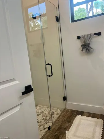 Bathroom featuring wood finished floors and a shower stall