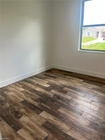 Spare room with baseboards and dark wood finished floors