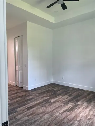 Spare room featuring dark wood finished floors and a tray ceiling