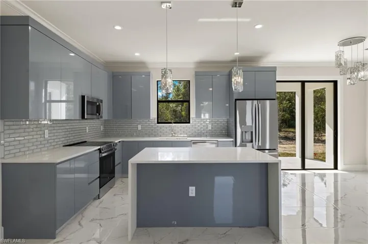 Kitchen featuring appliances with stainless steel finishes, tasteful backsplash, hanging light fixtures, and crown molding
