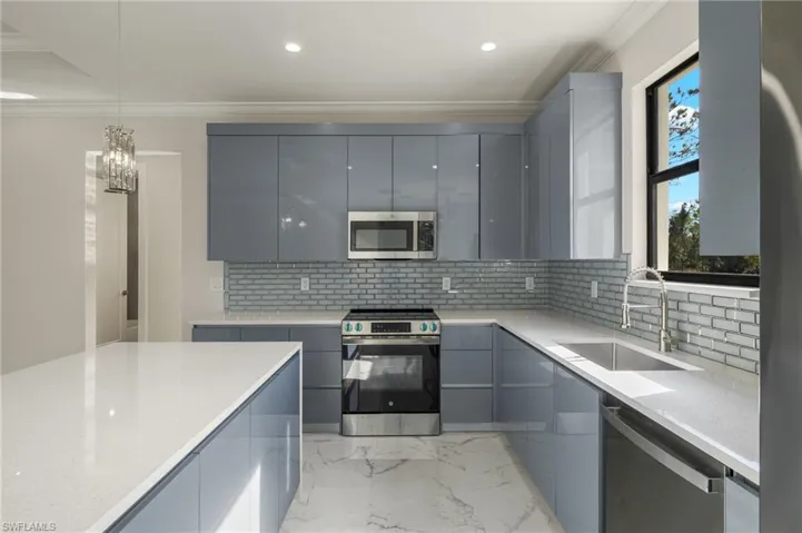 Kitchen featuring backsplash, gray cabinetry, sink, and stainless steel appliances