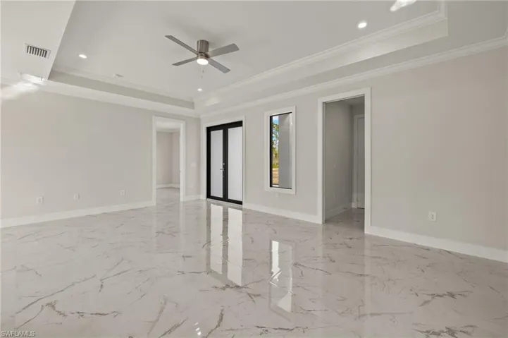 Unfurnished room featuring a tray ceiling, ceiling fan, and crown molding