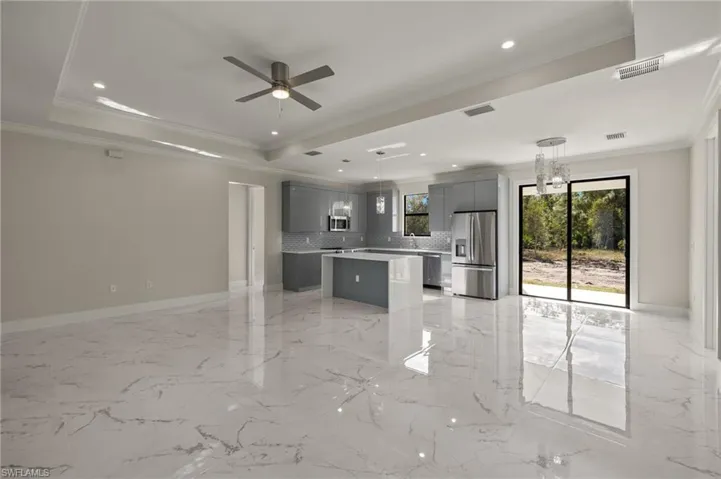 Kitchen with gray cabinets, a kitchen island, stainless steel appliances, and hanging light fixtures