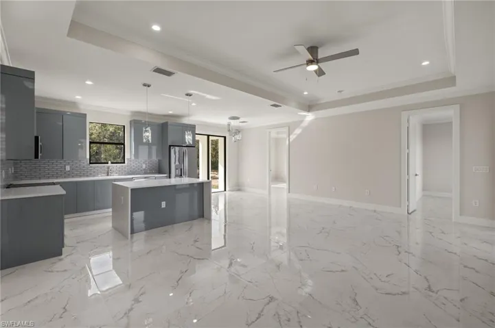 Kitchen with stainless steel fridge, a kitchen island, hanging light fixtures, and a tray ceiling
