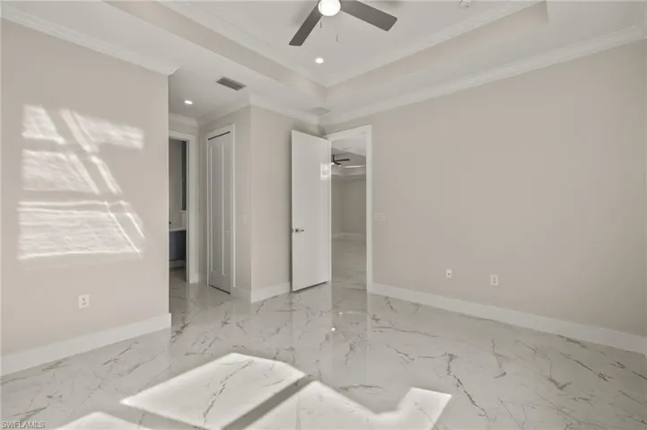 Unfurnished room with a tray ceiling, ceiling fan, and crown molding