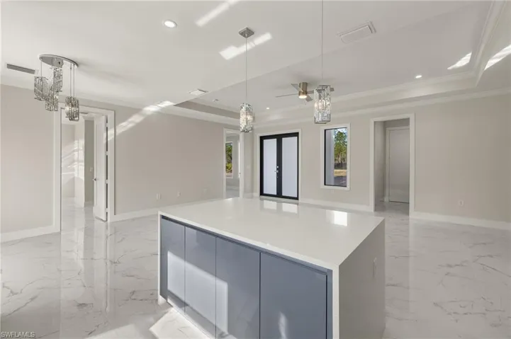 Kitchen with a kitchen island, decorative light fixtures, a raised ceiling, and crown molding