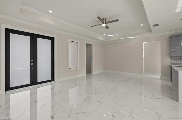 Spare room featuring french doors, a raised ceiling, ceiling fan, and crown molding