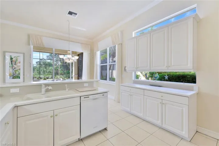 Kitchen featuring dishwasher, sink, hanging light fixtures, white cabinetry, and a chandelier