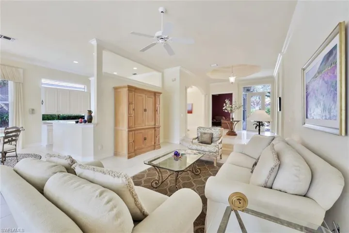 Tiled living room featuring crown molding and ceiling fan
