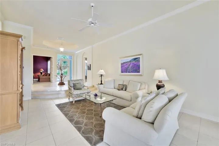 Tiled living room with ceiling fan and crown molding