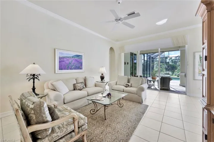 Tiled living room featuring ceiling fan and ornamental molding