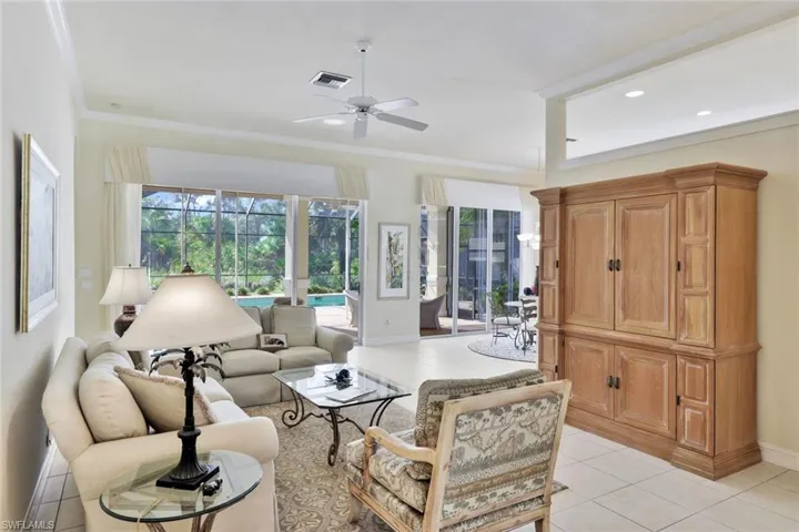 Living room featuring ceiling fan, light tile patterned floors, and crown molding