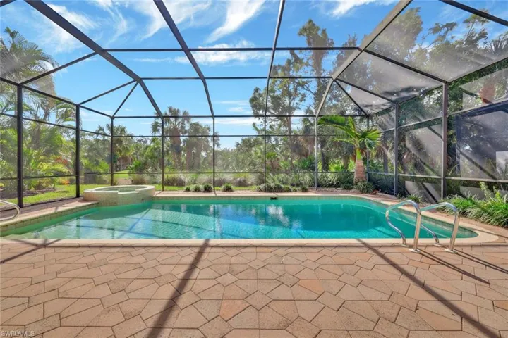 View of swimming pool featuring glass enclosure, an in ground hot tub, and a patio area
