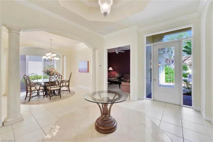 Tiled entrance foyer with ornate columns, a wealth of natural light, and ornamental molding
