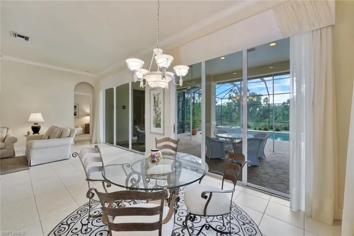 Dining space with ornamental molding, a notable chandelier, and light tile patterned flooring