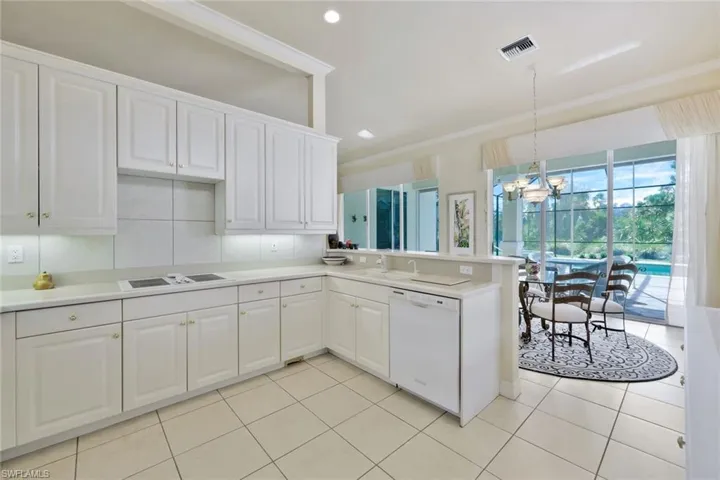 Kitchen with light tile patterned floors, white cabinets, decorative light fixtures, and white appliances