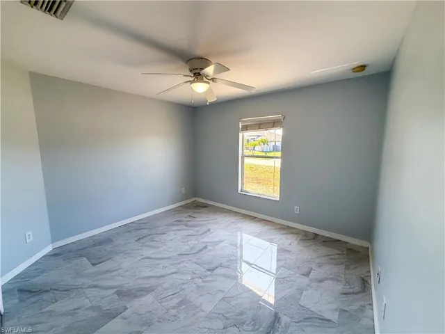 Unfurnished room featuring a ceiling fan and light marble finish flooring