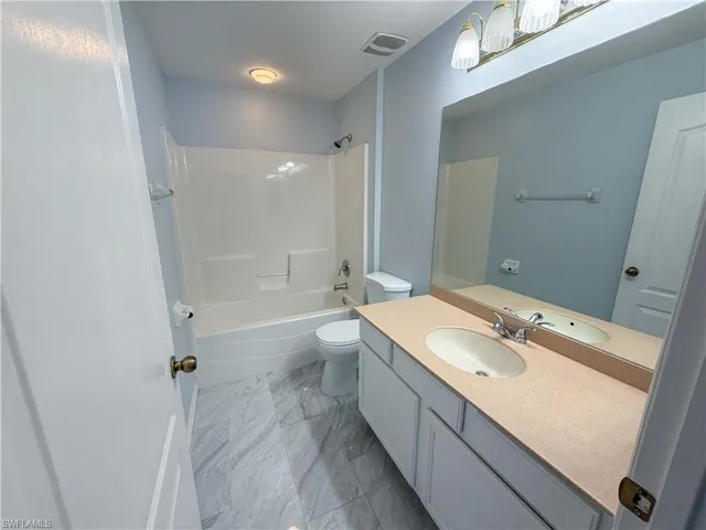 Bathroom with vanity, shower / tub combination, and light marble finish floors