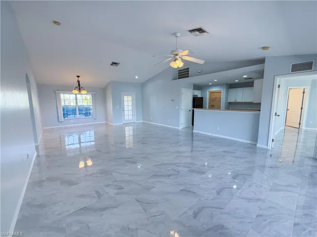 Unfurnished living room with a ceiling fan, lofted ceiling, light marble finish floors, and recessed lighting